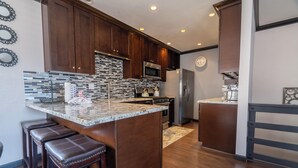A modern kitchen with dark wood cabinets, a granite countertop, and stainless steel appliances.
