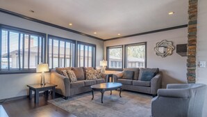 A spacious living room with a sectional sofa, a round coffee table, and a grey armchair.