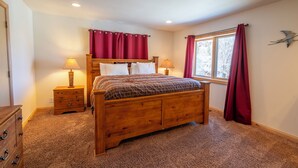 A bedroom with a wooden bed, two bedside tables with lamps, a window with red curtains, and a wall-mounted bird decoration. - Johnson Suite 2- Walk to both June and Gull Lakes, only 1.5 miles to June Mtn Ski Area (June Lake)
