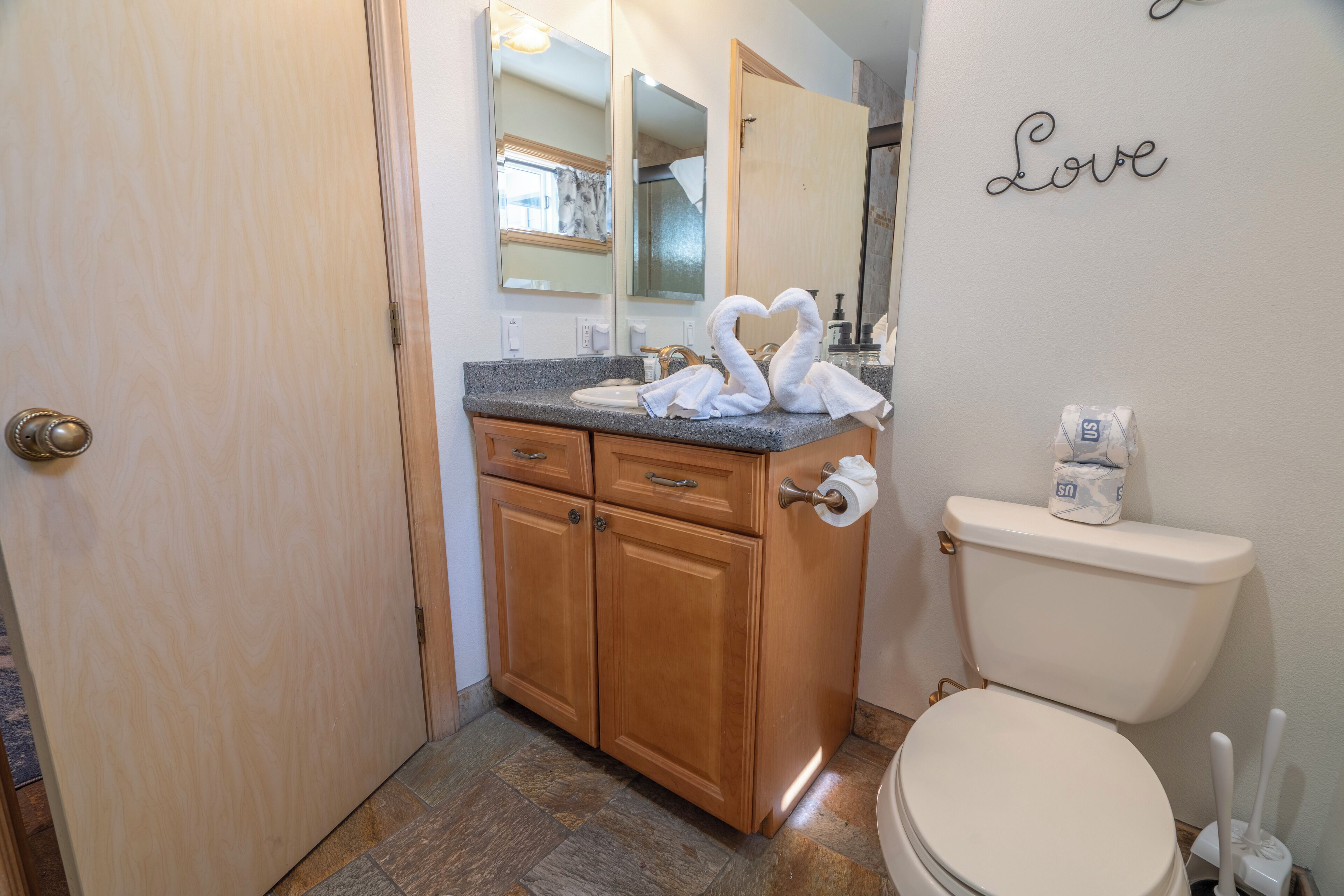 Un baño con muebles de madera, un lavabo, un inodoro y un espejo.