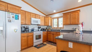 A kitchen with wooden cabinets, a white refrigerator, a microwave, a stove, and a window. - Johnson Suite 2- Walk to both June and Gull Lakes, only 1.5 miles to June Mtn Ski Area (June Lake)