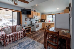 A cozy kitchen with wooden cabinets, a microwave, stove, and a dining area with a table and chairs.