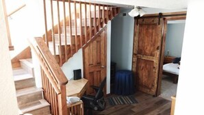 Een houten trap die leidt naar een slaapkamer met een bed en een nachtkastje.