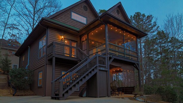 Eine zweistöckige Holzhütte mit Balkon, Treppe und Veranda.