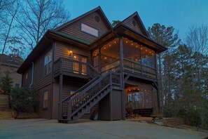 Eine zweistöckige Holzhütte mit Balkon, Treppe und Veranda.