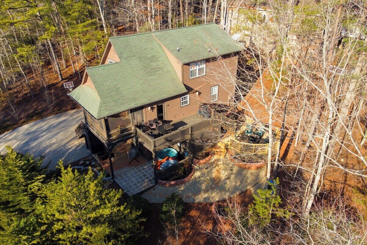 A two-story house with a green roof, a covered porch, and a swimming pool.