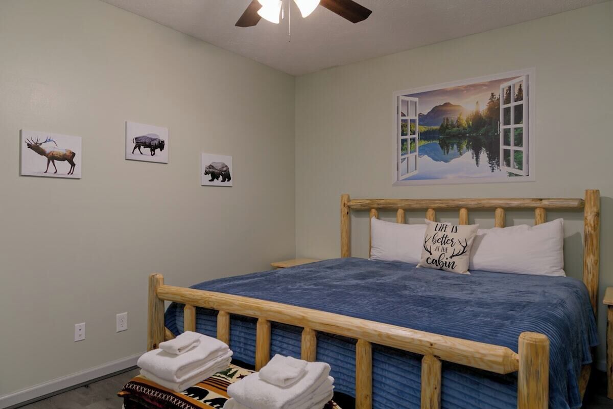 A bedroom with a wooden bed, a blue bedspread, and three animal-themed wall art pieces.