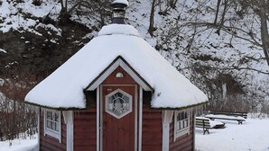 En lille træhytte med et sneklædt tag og et sekskantet vindue.