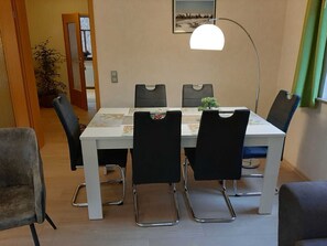 A dining area with a table, chairs, a lamp, and a framed picture on the wall.