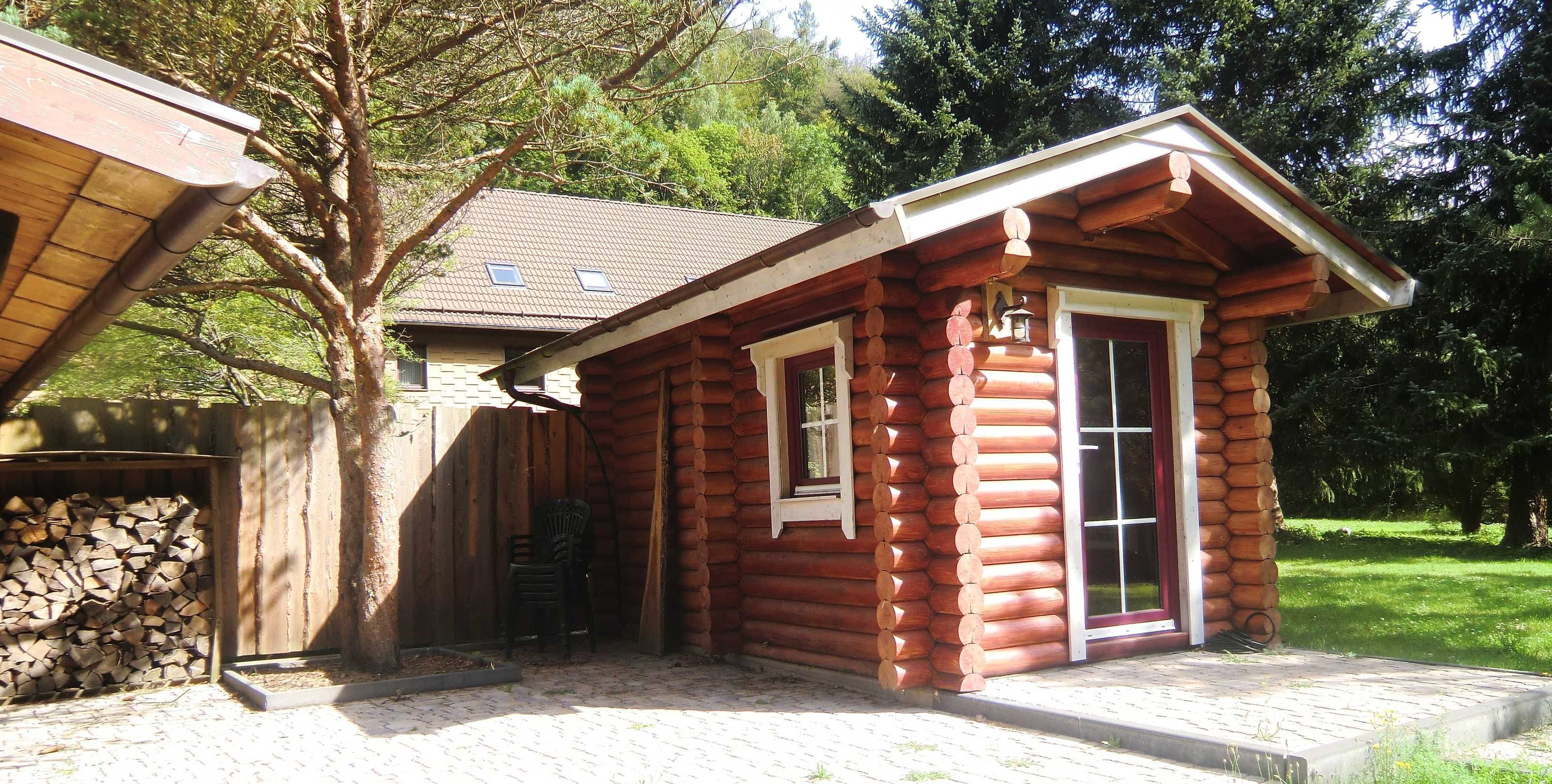 Une petite cabane en rondins, avec une cheminée, une fenêtre et une porte.