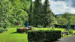 A lush garden with a wooden deck, outdoor seating, and a gazebo. - Staufenberg Vacation Rental - House in Wolfsbach - Vacation Apartments (Walkenried)