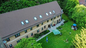 A multi-story building with a tiled roof, multiple windows, and a small courtyard with a lawn and a gazebo. - Staufenberg Vacation Rental - House in Wolfsbach - Vacation Apartments (Walkenried)