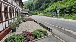 A building with a sign reading 'Bau am Wolfsbach' and a gravel pathway with potted plants.