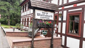 A traditional half-timbered building with a sign reading 'Haus am Wolfsbach Ferienwohnungen' and a beer sign below. - Staufenberg Vacation Rental - House in Wolfsbach - Vacation Apartments (Walkenried)