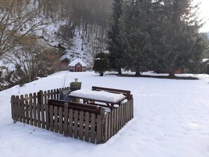 A snow-covered outdoor area with a wooden fence, a bench, and a small building in the background. - Staufenberg Vacation Rental - House in Wolfsbach - Vacation Apartments (Walkenried)