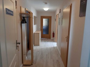 A hallway with wooden doors, a coat rack, a fire extinguisher, and a sign that reads 'Staufenberg.' - Staufenberg Vacation Rental - House in Wolfsbach - Vacation Apartments (Walkenried)
