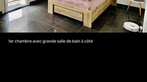 A bedroom with a large sliding glass door to the outside, a bed with a wooden frame, a small bedside table, and a wall-mounted light fixture. - Very nice 80 m2 apartment (Pianottoli-Caldarello)