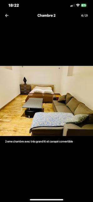 Habitación de dos dormitorios con cama balinesa convertible, un sofá y una mesita.