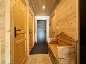 A hallway with wooden walls and doors, a bench, and a dark-colored door at the end. - 4-room apartment for 10/12 people in Briançon with Wifi (Briançon)