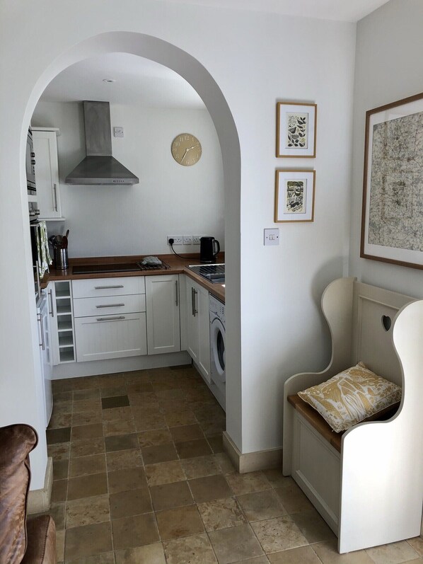 A compact kitchen with white cabinets, a washing machine, and a clock on the wall.