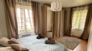 Une chambre à coucher avec un grand lit, deux oreillers, un tapis et un luminaire suspendu.