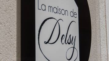 Letrero con el texto 'La maison de Delsey' en una tipografía estilizada.