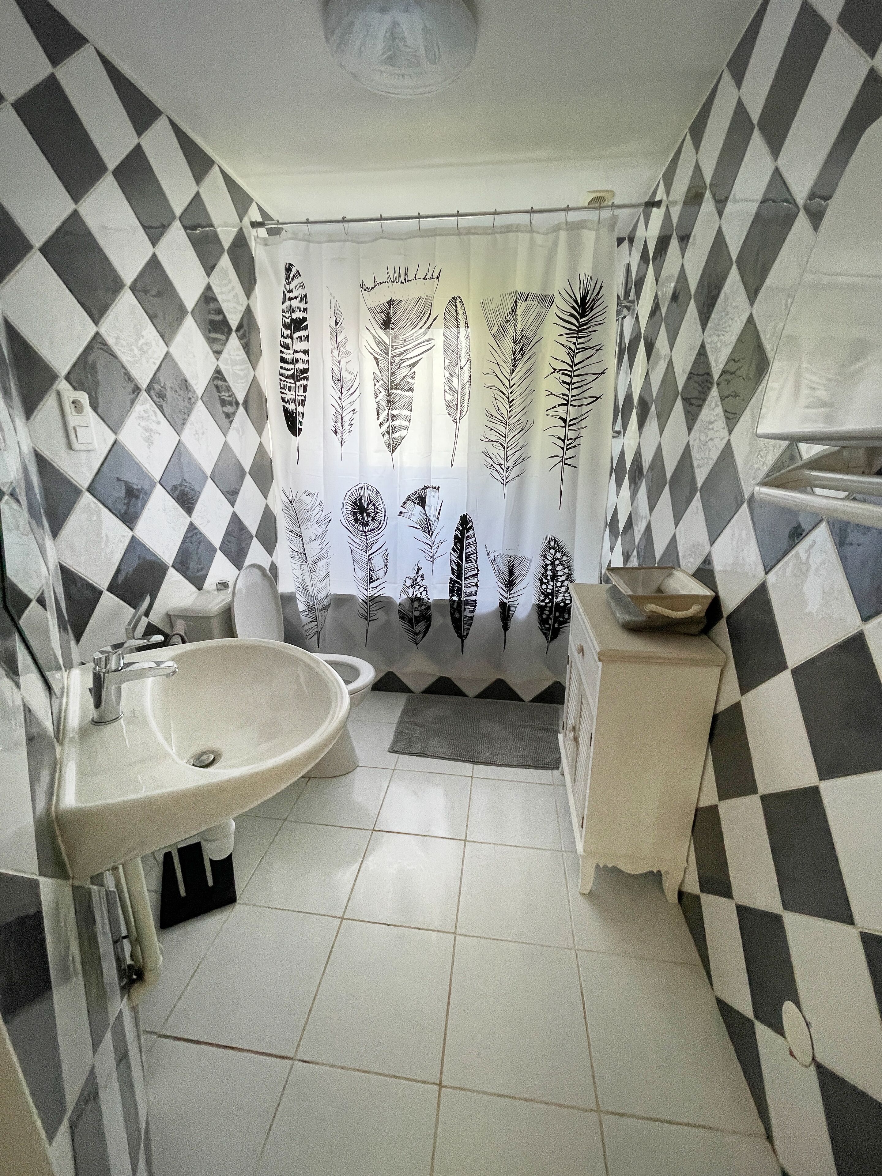 Ein Badezimmer mit Waschbecken, Toilette und Duschvorhang mit Federprint.