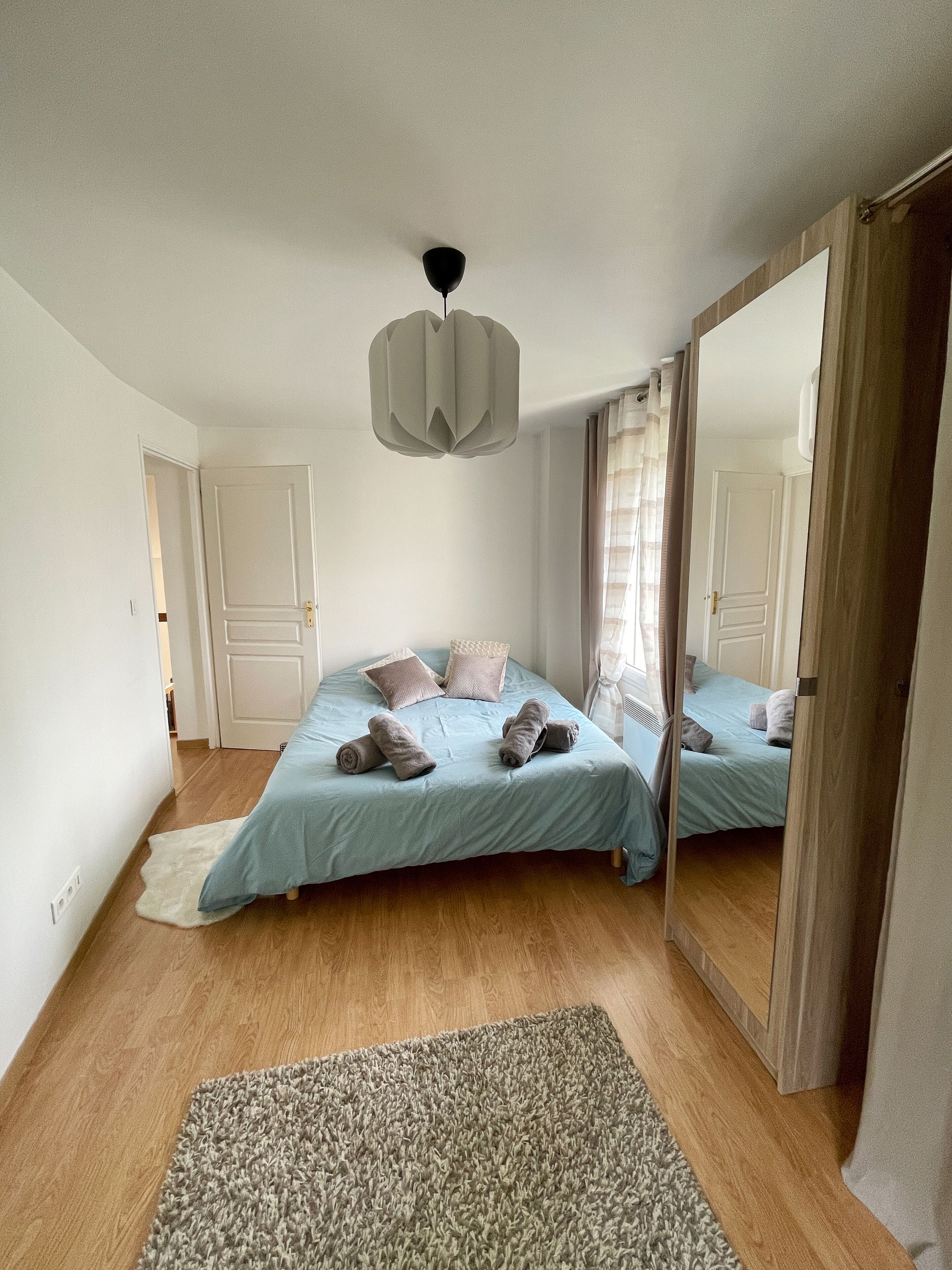 A bedroom with two beds, a large mirror, and a ceiling light fixture.