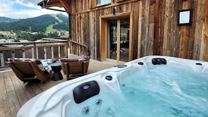 A wooden deck with a hot tub, outdoor seating, and a view of the mountains. - Spacious 5* chalet with jacuzzi and sauna, pets allowed (Les Gets)