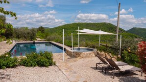 A swimming pool with a hot tub, surrounded by a stone deck and a white canopy. - Family Friendly Accommodation in Umbria (Perugia)