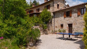 A stone building with a courtyard, a ping pong table, and surrounding greenery. - Family Friendly Accommodation in Umbria (Perugia)