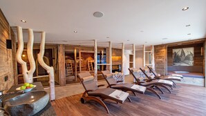 A spa area with wooden beams, a stone basin, and lounge chairs.