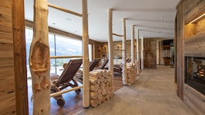 A spacious room with wooden beams, a fireplace, and a view of the mountains.