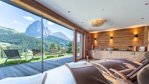 A modern interior with a large glass door leading to an outdoor deck, wooden flooring, and a view of mountains.