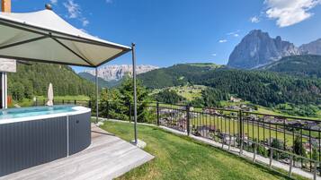 Un bain à remous doté d’un auvent, une terrasse en bois et une vue panoramique sur les montagnes.