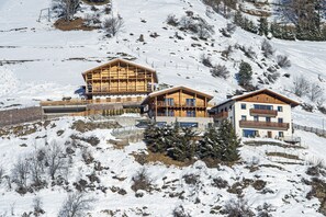 Een met sneeuw bedekte berg met twee houten gebouwen, waarvan er één een balkon heeft en de ander een houten gevel.