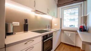 Een moderne keuken met een inbouwoven, een kookplaat en een raam met uitzicht op gebouwen.