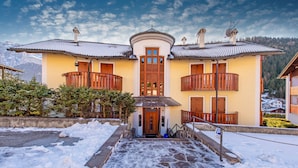 Un bâtiment à deux étages, doté d’une entrée centrale, de balcons et d’un sol recouvert de neige.
