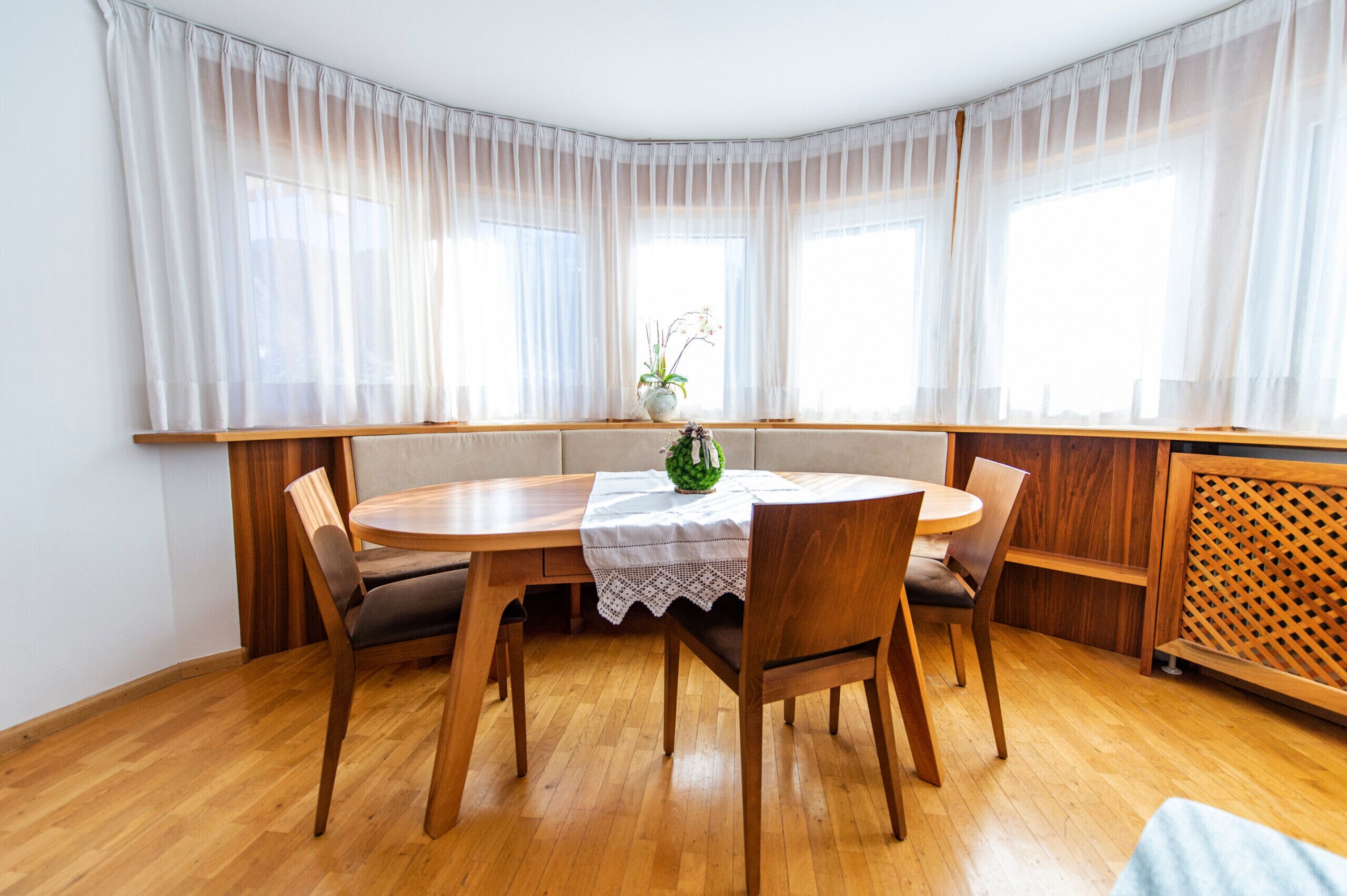 Un coin repas avec une table ronde, quatre chaises et un banc placé le long de la fenêtre.