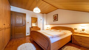 Une chambre à coucher en bois, avec un lit, des tables de chevet, un miroir et un lustre.
