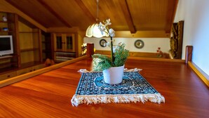 Une table de salle à manger en bois, agrémentée d’un set de table à motifs et d’une plante en pot.