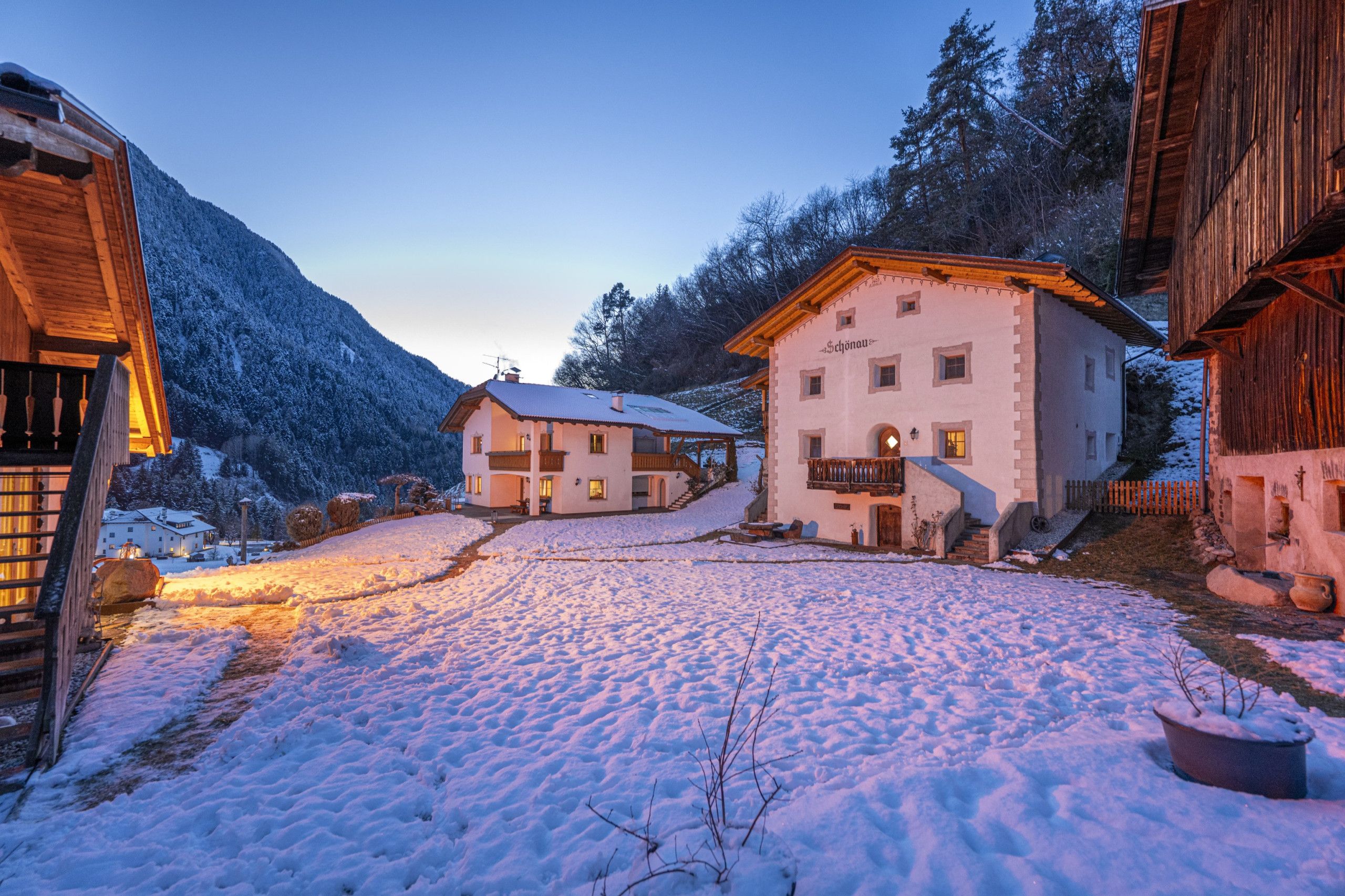 A snow-covered village with traditional buildings, a clear sky, and a mountain in the background.