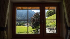 A window with a view of a green landscape, a wooden ceiling, and a metal railing. - Bio & Family Apartments Schoenau 155A (Ortisei)