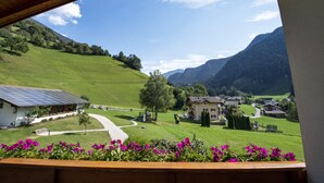 Ein malerischer Blick auf ein ländliches Dorf mit Häusern, einer kurvenreichen Straße und Bergen im Hintergrund.