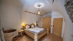Een slaapkamer met een houten bed, een stenen wasbak en een houten deur.