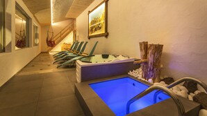 A spa area with a hot tub, wooden chairs, and a framed picture on the wall.