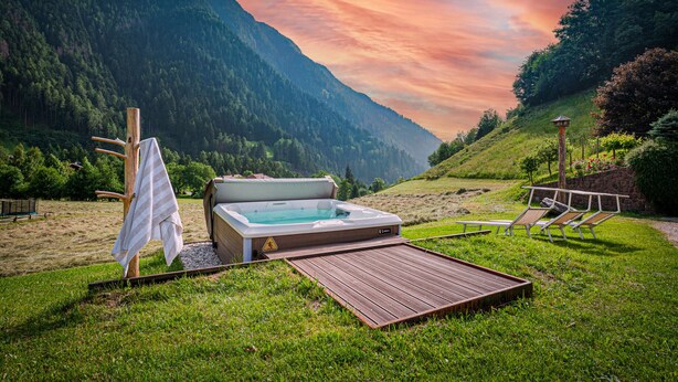 A hot tub in a grassy area with a mountain backdrop.