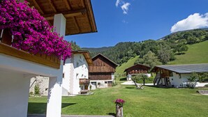 A traditional chalet with a wooden facade, a stone foundation, and a lush green lawn.
