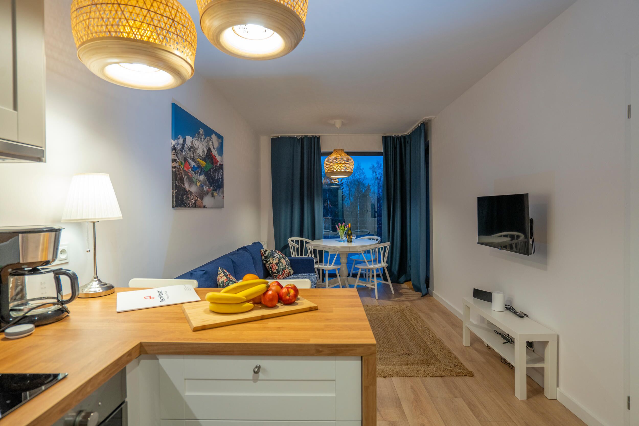 A modern kitchen with a wooden countertop, a coffee maker, and a dining area with a table and chairs.