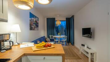 A modern kitchen with a wooden countertop, a coffee maker, and a dining area with a table and chairs.